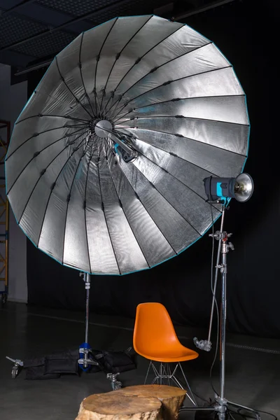 Empty photo studio with modern interior and lighting equipment. Preparation for studio shooting: empty chair and studio lighting.