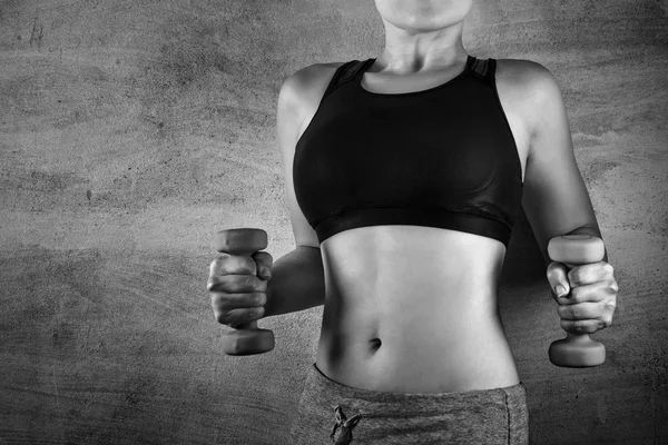 Fit woman exercising with weights on the background of a concrete wall in the gym. No face, healthy lifestyle concept.