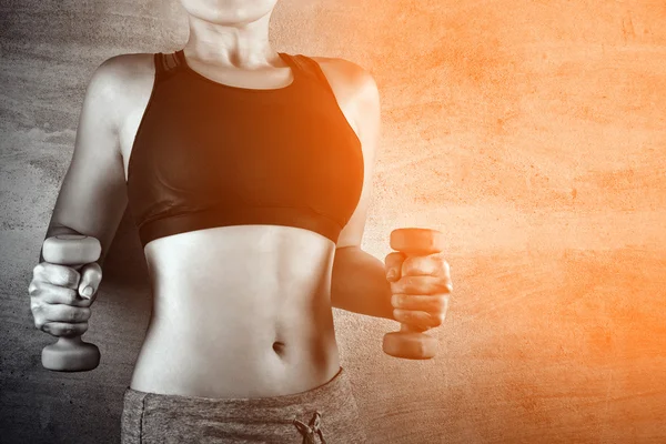 Fit woman exercising with weights on the background of a concrete wall in the gym. No face, healthy lifestyle concept.