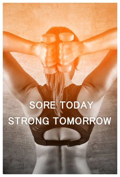 Sore today strong tomorrow. Inspiration quote. Fit woman exercising with weights on the background of a concrete wall in the gym. Healthy lifestyle concept.