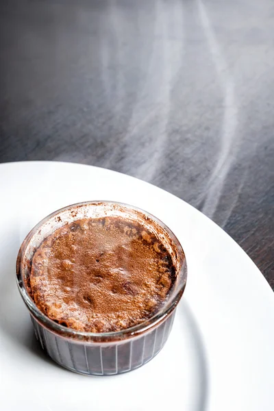 Freshly baked steaming hot dessert chocolate fondant lava cake served on white plate. Famous French dessert on dark wooden table top view.