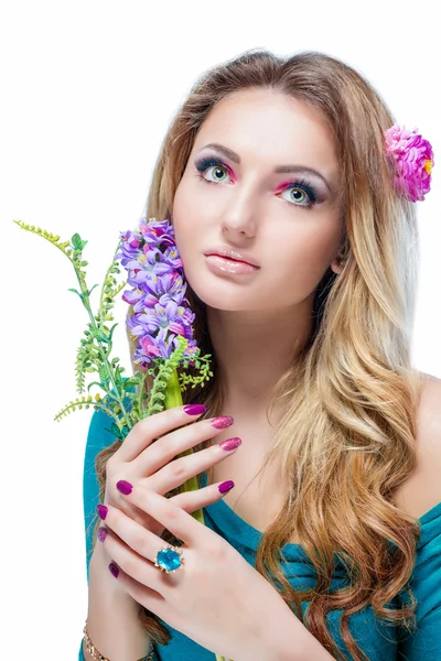 Beautiful blonde girl with bright makeup, long curled hair and massive jewelry holding a blossoming branch isolated on white background. Fashion shot.