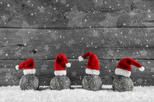 Grey festive wooden christmas background with four santa hats on