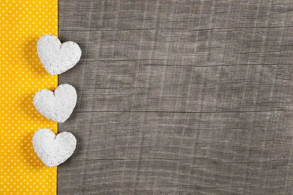 Wooden background with three white and yellow hearts on wooden b