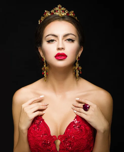 Beautiful girl in a golden crown and earrings on a dark backgrou