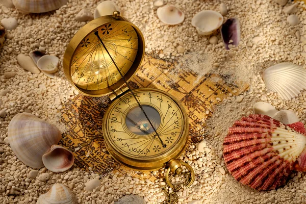 Ancient compass on the sand with seashells