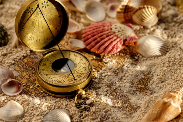 Ancient compass on the sand with seashells