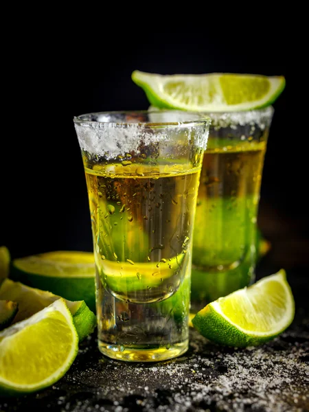 Mexican Gold Tequila with lime and salt on black table