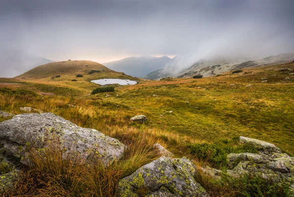 Foggy Mountain Landscape with a Tarn at Sunset