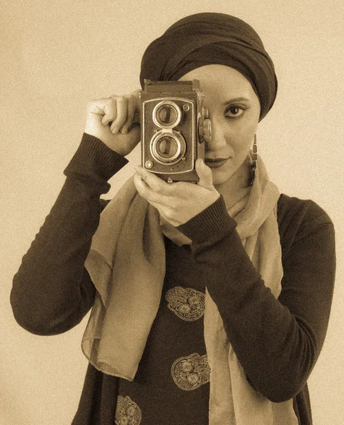 Young Woman holding old camera in hijab and scarf