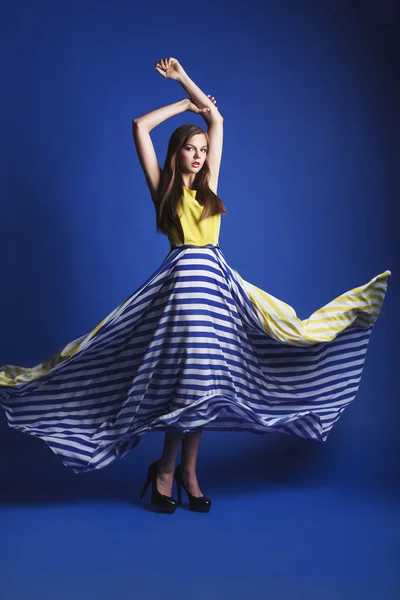 Beautiful woman in long yellow blue dress posing dynamic in the