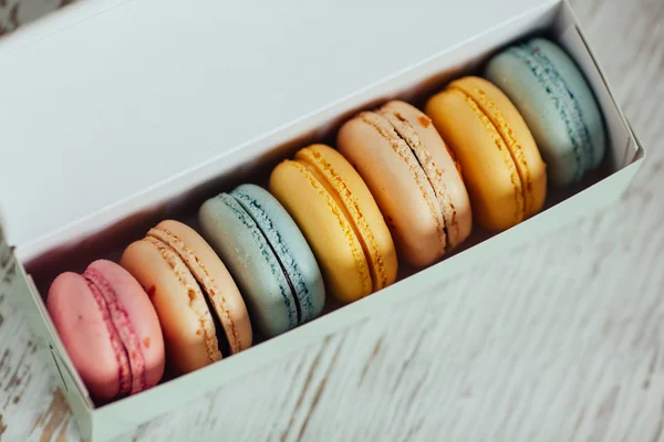 Colorful Macaroons in the box on wooden white background