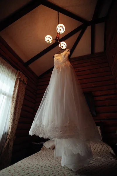 Wedding dress hanging on luster at hotel room