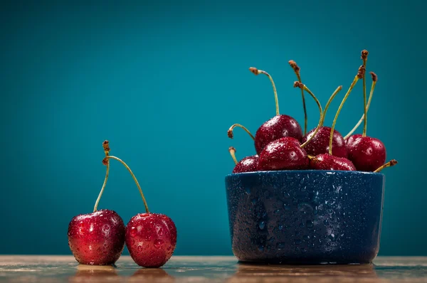 Fresh ripe Cherries on wooden table with water drops blue background.