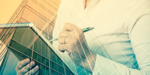 Business, people and technology concept - double exposure businesswoman with notebook over city background