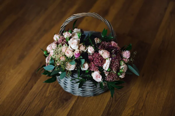 Beautiful basket of flowers on the wooden floor, top view.