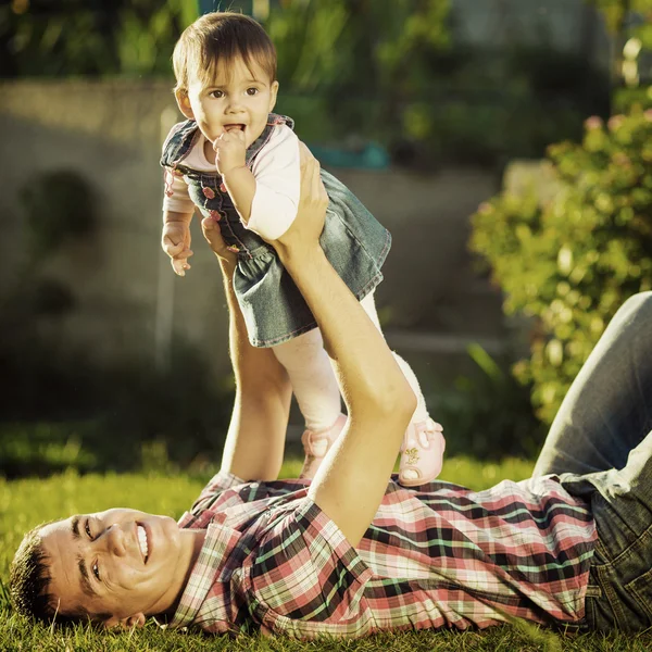 Father and baby daughter having fun in sunny garden.
