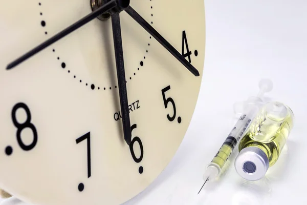 Medicine vials and syringe, the clock shows the time of the medi