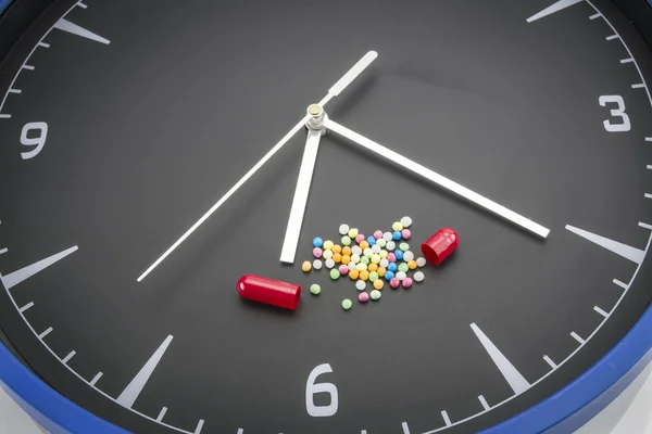 Open red capsule pill with white powder drug on black clock back