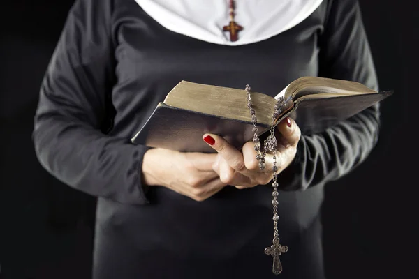 Nun hands holding bible book over grey background
