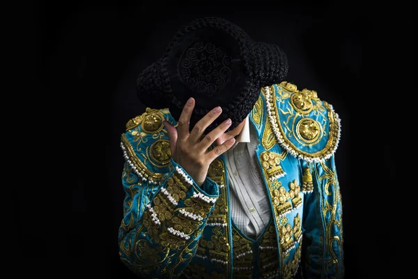 Woman bullfighter salutes with his montera in black background