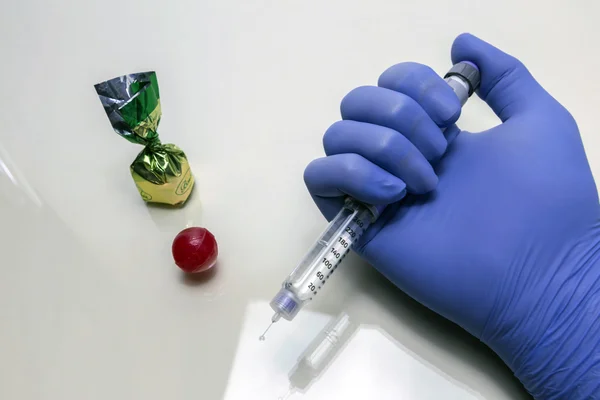 Blue-gloved hand holds a syringe of insulin together with some s