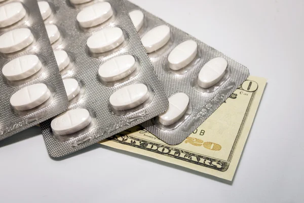 Blister of white pills on top of banknotes of 20 dollars, concept of health copay