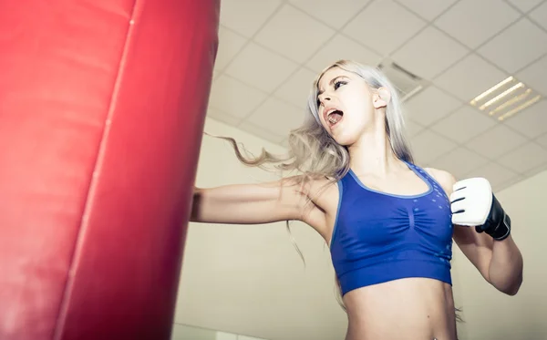 Woman hits the boxing heavy bag in the gym