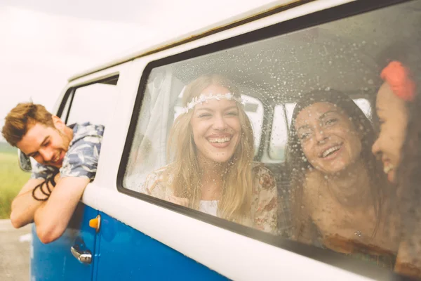 Hippie friends having fun into a vintage van, taking a break aft