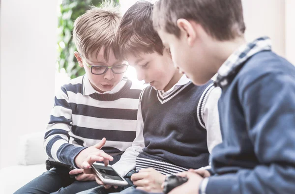 Three children using smart phone and learning about techology