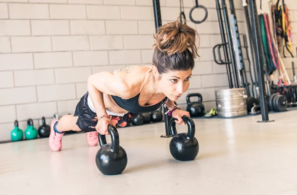 Woman making push ups on the kettle bells