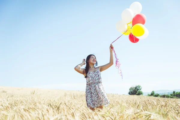 Woman with balloons in a wheat field