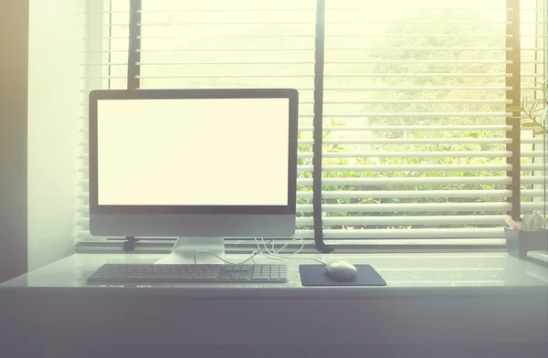 Computer on white desk beside window