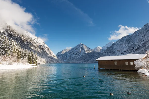 Boat house in austrian lake at snowy and sunny winter landscape