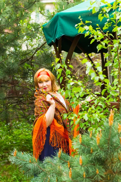 Cheeked Russian cheerful young woman in the green of spring foli