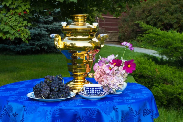 The end of the summer. Samovar, cups of tea and autumn gifts - flowers, vegetables and fruit