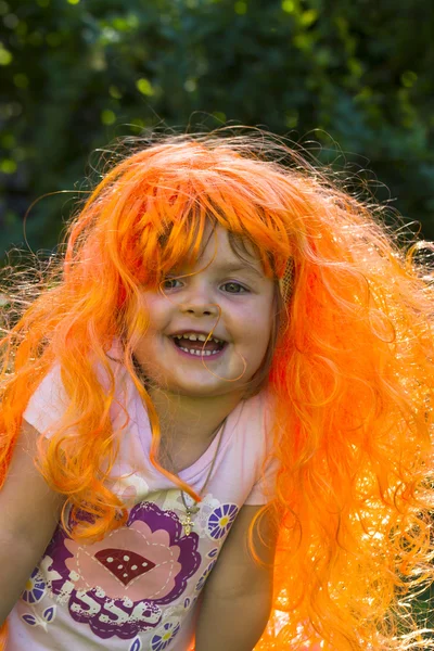 Portrait of a little girl in the carnival wig of hair color