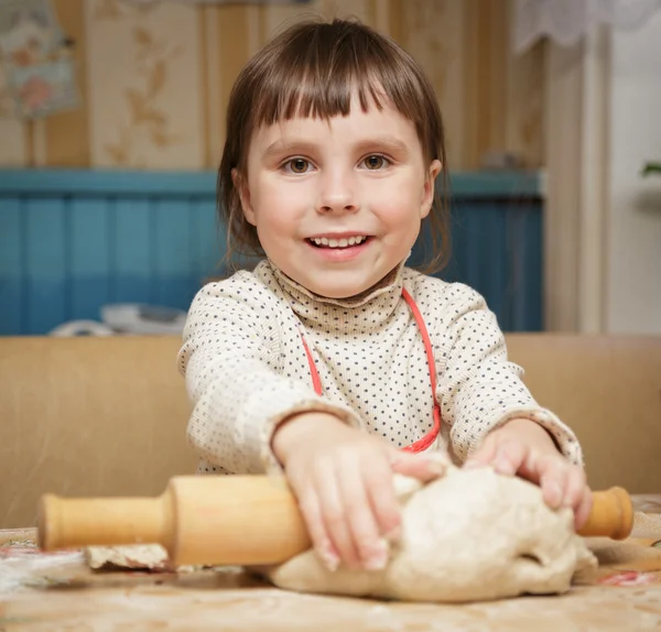 Little cute girl rolls the dough