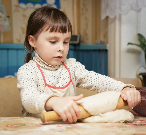 Little cute girl rolls the dough