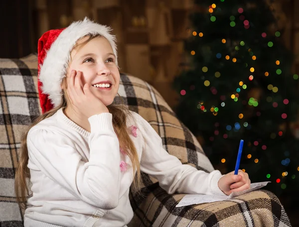 Joyful girl writes a letter to Santa Claus
