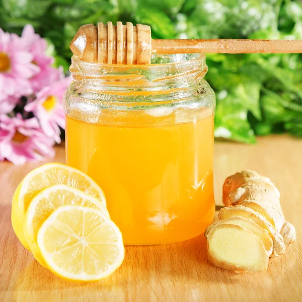 Honey, ginger, lemon on a wooden surface in the background of nature