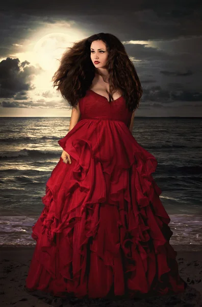 Beautiful Mysterious woman in long red dress at ocean beach. Fantasy woman. Water Goddess. Book cover.