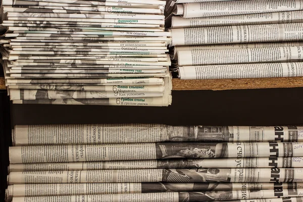 A stack of old newspapers lie on the shelf