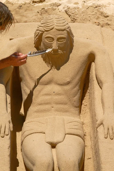 Young Man Working on Sand Sculpture of Jesus in Cadiz, Spain