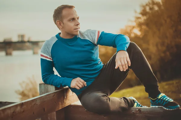 Attractive man sitting on beach in the evening  after sport