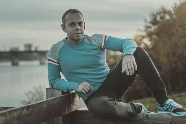 Attractive man sitting on beach in the evening  after sport.