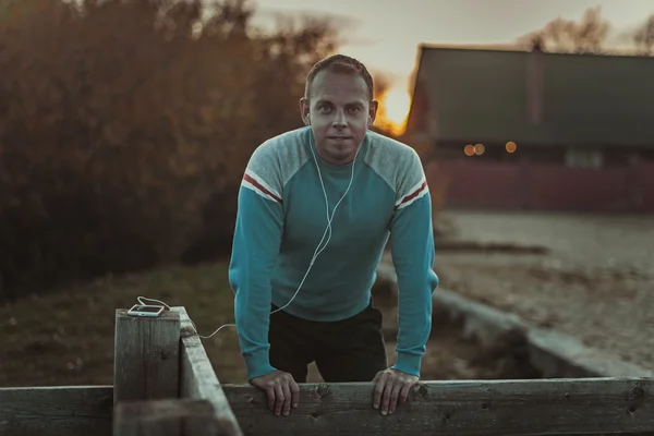 Attractive man sitting on  beach in the evening sunset after sport