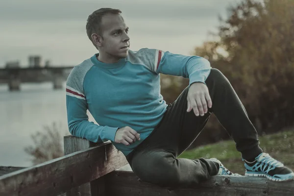 Attractive man sitting on beach in the evening  after sport.