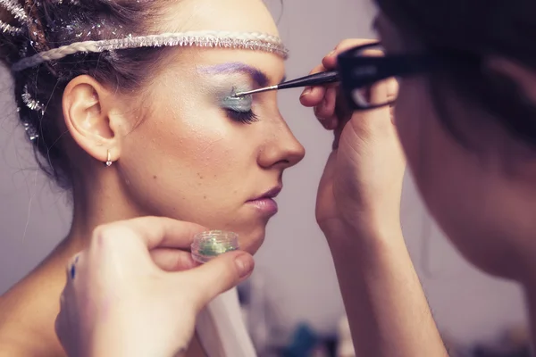 Make up artist woman applying make up for a brunette model for a