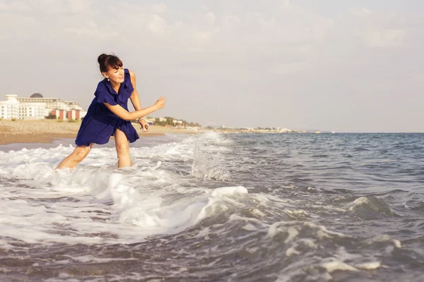 Woman throwing rocks on a  sand seashore near sea looking on the